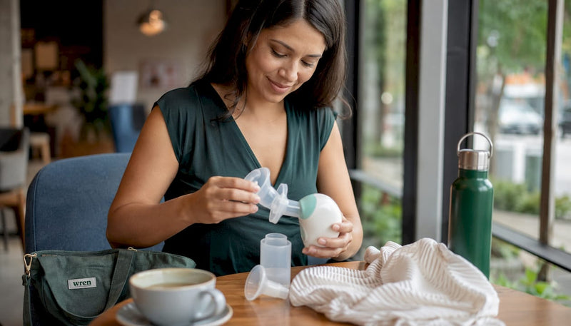 Mother preparing wearable breast pump in hotel room