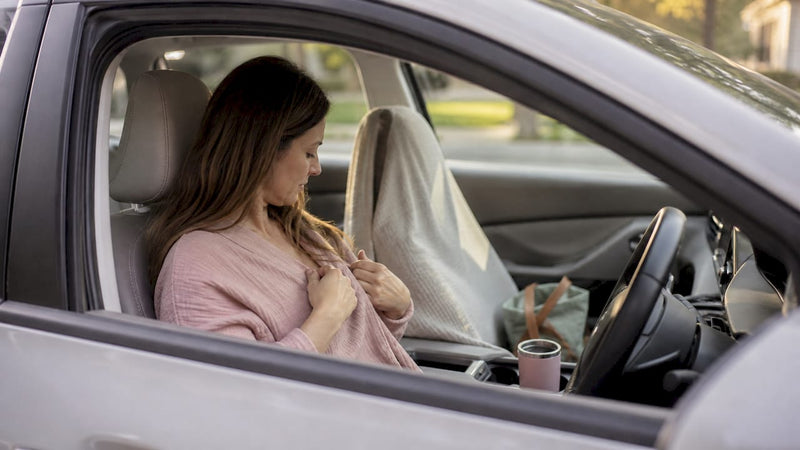 Mother pumping breast milk inside a parked car