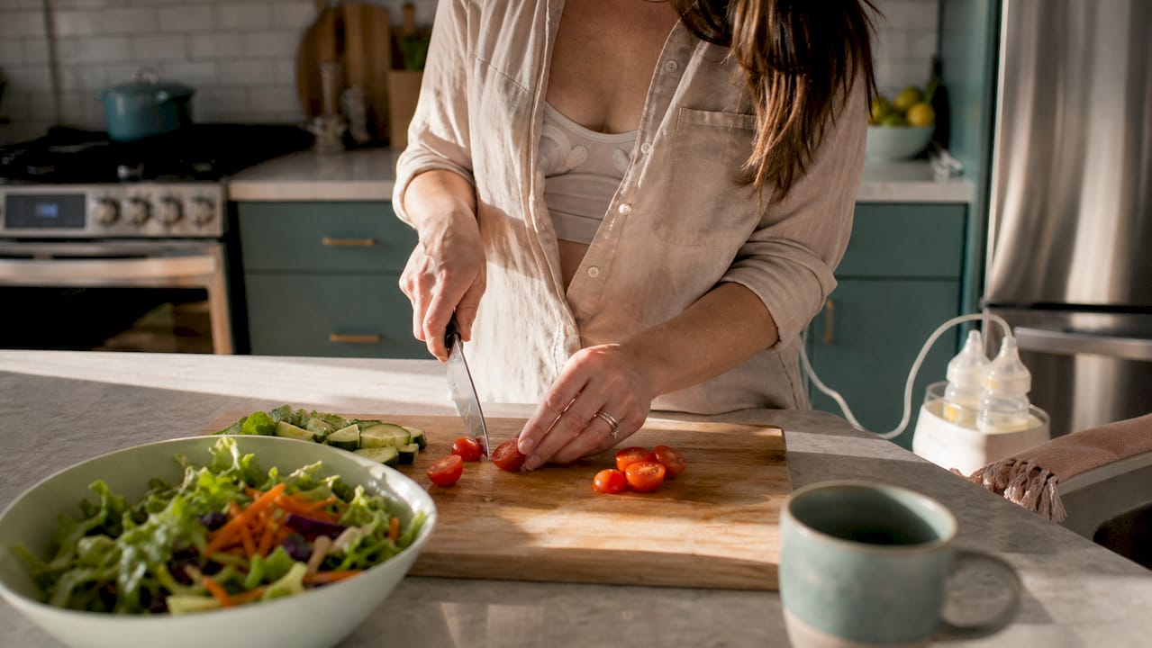 Mother hands-free pumping milk in kitchen