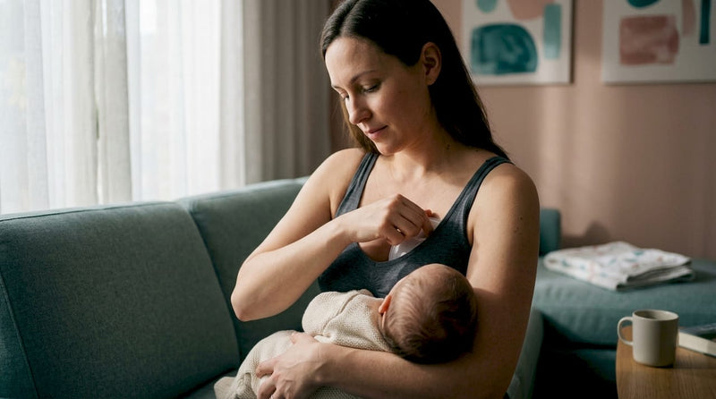 Mother wearing a discreet breast pump while breastfeeding
