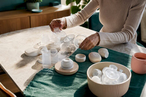 Hands comparing anonymous breast pump components Featured Image