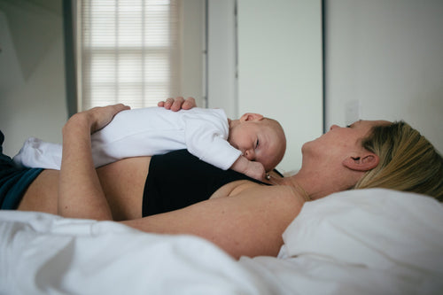 A baby lying on top of it's mother Featured Image