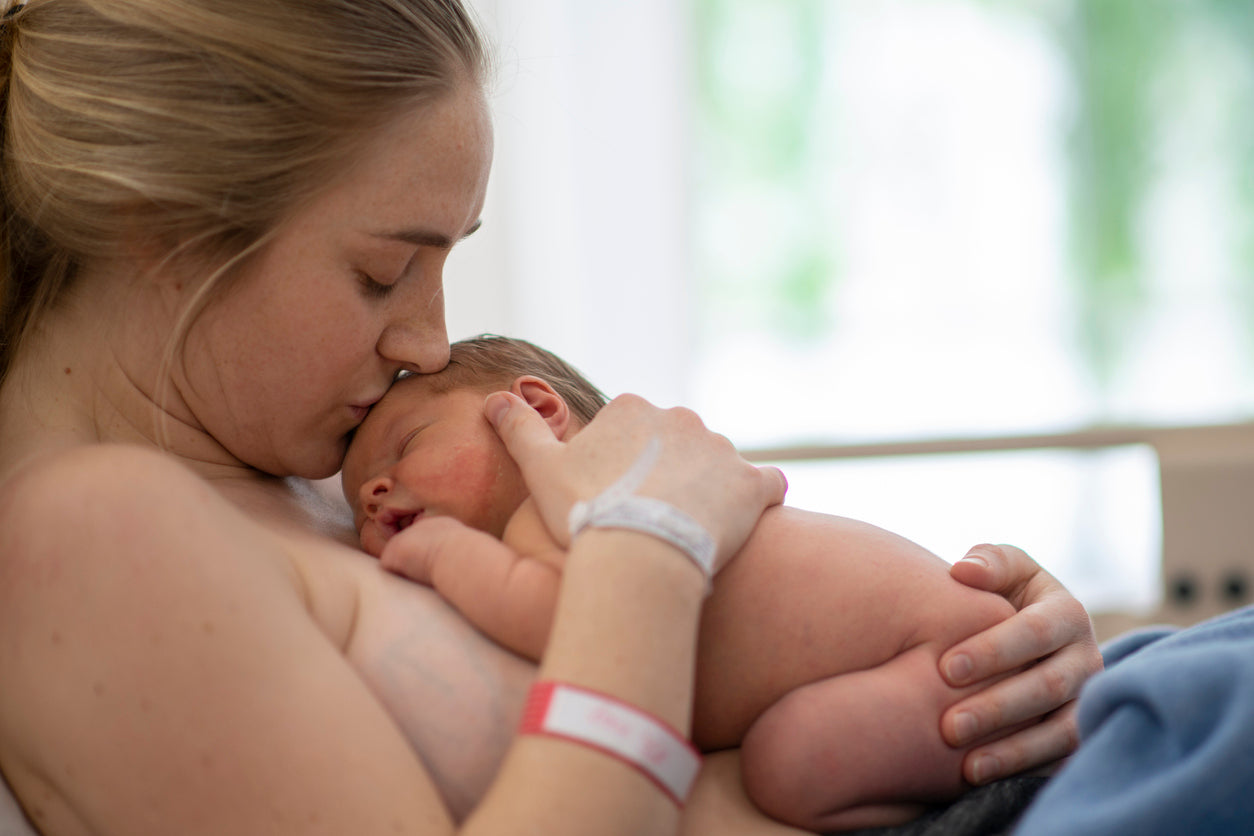 A woman holding and kissing her baby close